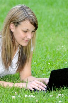 Young woman with netbook on meadow