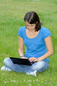 Teenage girl with netbook on meadow