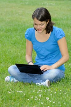 Teenage girl with netbook on meadow