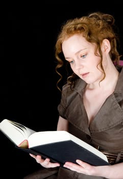 Beautiful girl with red hair reading a book