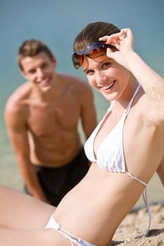 Young couple sunbathing by sea on beach