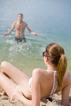 Young couple - woman sunbathing on beach