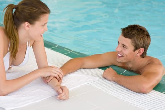 Swimming pool - young loving couple hold hands