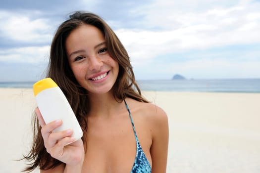 Woman showing sunscreen on the beach