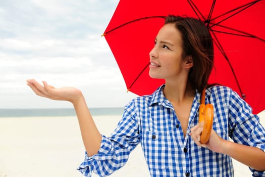 Rain woman with umbrella on the beach