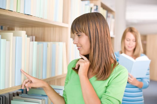 Student in library - two woman choose book