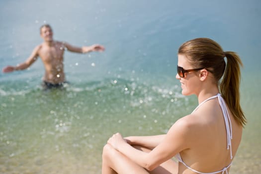Young couple - woman sunbathing on beach