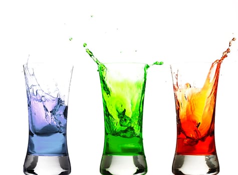Ice cubes falling into colorful glasses