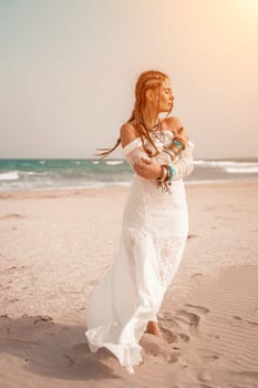 woman sea white dress. Model in boho style in a white long dress and silver jewelry on the beach. Her hair is braided, and there are many bracelets on her arms