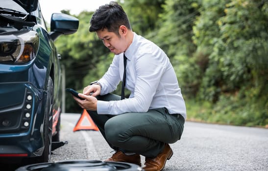 Portrait man sitting while calling roadside assistance after breaking down. Elegant middle age businessman wearing white shirt and waiting for help car accident on road. Roadside assistance concept.