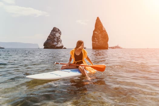 Close up shot of beautiful young caucasian woman with black hair and freckles looking at camera and smiling. Cute woman portrait in a pink bikini posing on a volcanic rock high above the sea