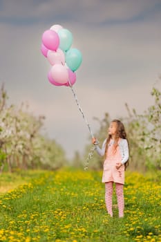 girl with balloons in a young apple orchard