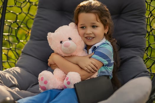 Portrait of a little girl hugging a teddy bear outdoors