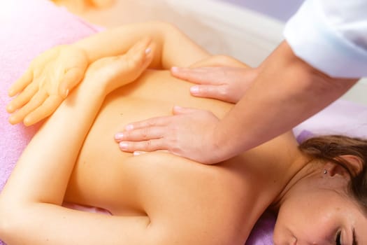 Top view of hands massaging female abdomen.Therapist applying pressure on belly. Woman receiving massage at spa salon.