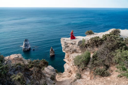 A woman in a red flying dress fluttering in the wind, against the backdrop of the sea