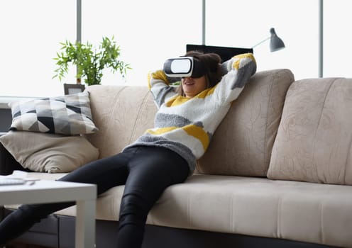 Portrait of female lay casually on couch in vr glasses, use modern device at home, test new development. Visual effect, innovation, entertainment concept