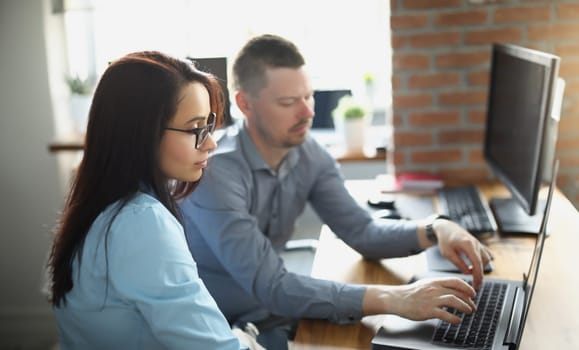 Portrait of male colleague help female coworker with work, explain on laptop, office life, corporation, business, education, teamwork, progress concept