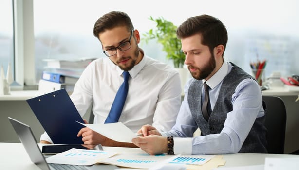 Portrait of coworkers men go through financial papers, solve and discuss problems. Fresh look on situation, new angle, white collar. Investment concept