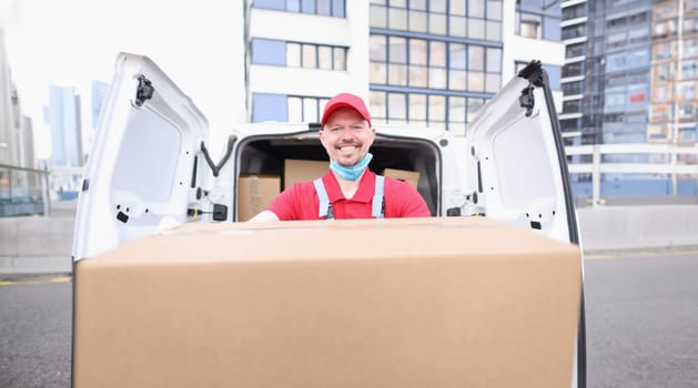 Portrait of happy postman worker carry cardboard package, delivery on address, courier work for shipping company. Private delivery service, order concept