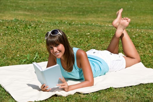 Smiling young woman read book in park