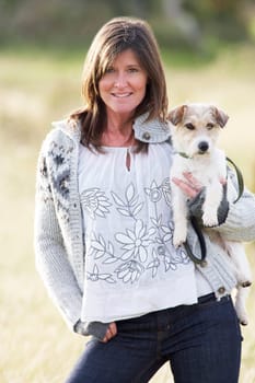 Young Woman Outdoors In Autumn Landscape Holding Dog