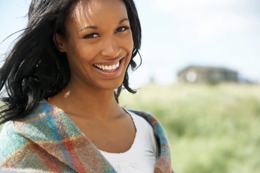 Thoughtful Young Woman Standing On Beach Wrapped In Blanket