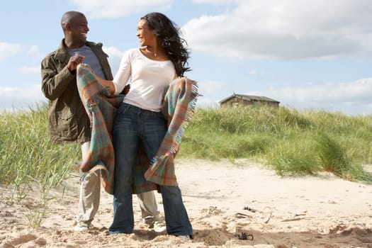 Romantic Young Couple Standing By Dunes With Beach Hut In Distance
