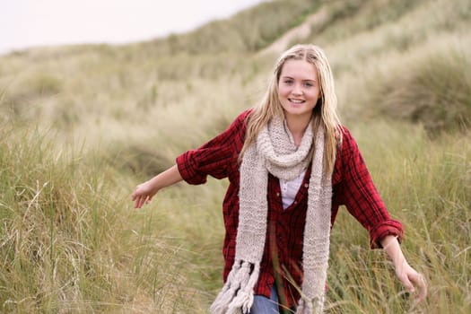 Teenage Girl Walking Through Sand Dunes Wearing Warm Clothing
