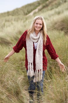 Teenage Girl Walking Through Sand Dunes Wearing Warm Clothing