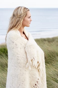 Young Woman Standing In Sand Dunes Wrapped In Blanket