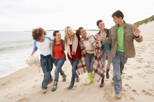 Group Of Young Friends Walking Along Autumn Shoreline