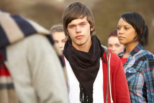 Teenage Boy Surrounded By Friends In Outdoor Autumn Landscape