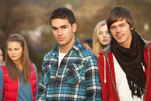 Teenage Boy Surrounded By Friends In Outdoor Autumn Landscape