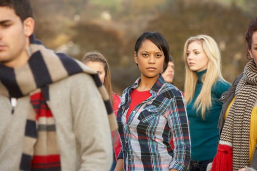 Teenage Girl Surrounded By Friends In Outdoor Autumn Landscape