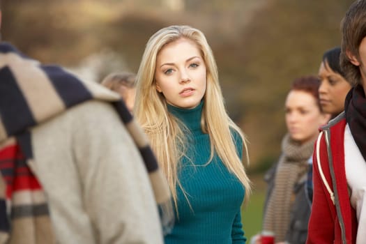 Teenage Girl Surrounded By Friends In Outdoor Autumn Landscape