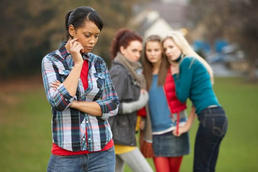 Upset Teenage Girl With Friends Gossiping In Background