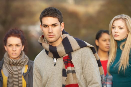 Teenage Boy Surrounded By Friends In Outdoor Autumn Landscape