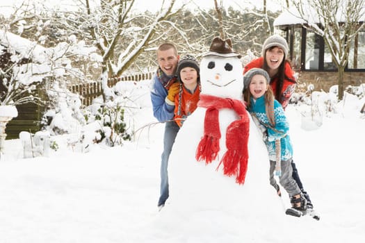 Family Building Snowman In Garden