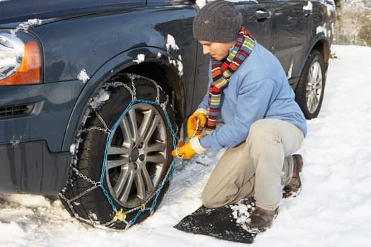 Man Putting Snow Chains Onto Tyre Of Car