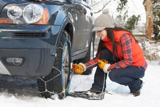 Woman Putting Snow Chains Onto Tyre Of Car