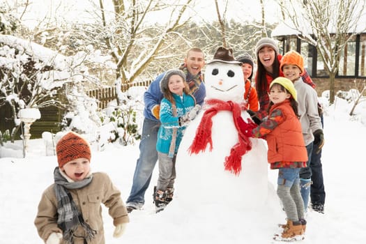 Family Building Snowman In Garden