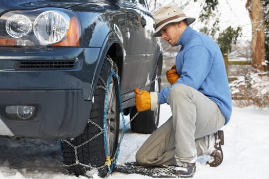 Man Putting Snow Chains Onto Tyre Of Car