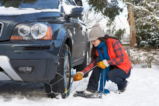 Woman Putting Snow Chains Onto Tyre Of Car
