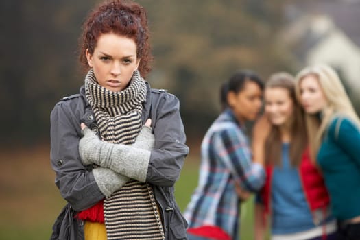Upset Teenage Girl With Friends Gossiping In Background