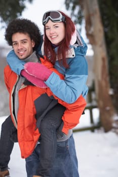 Teenage Boy Giving Girl Piggyback In Snowy Landscape