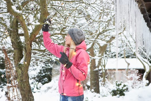 Teenage Girl Hanging Fairy Lights In Tree With Icicles In Foreground