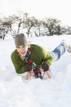 Young Man Riding On Sledge In Snowy Landscape