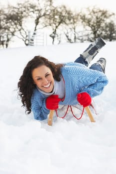 Young Woman Riding On Sledge In Snowy Landscape