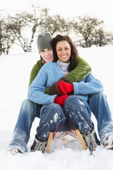 Couple Sledging Through Snowy Woodland