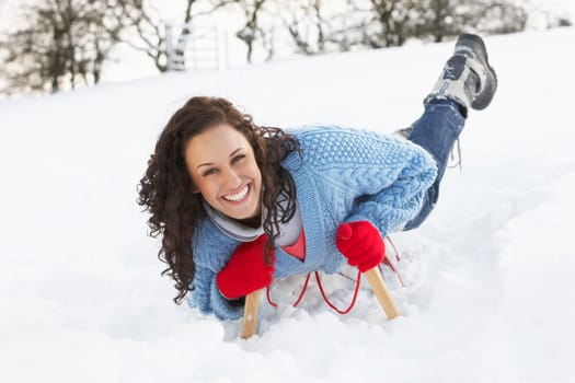 Young Woman Riding On Sledge In Snowy Landscape